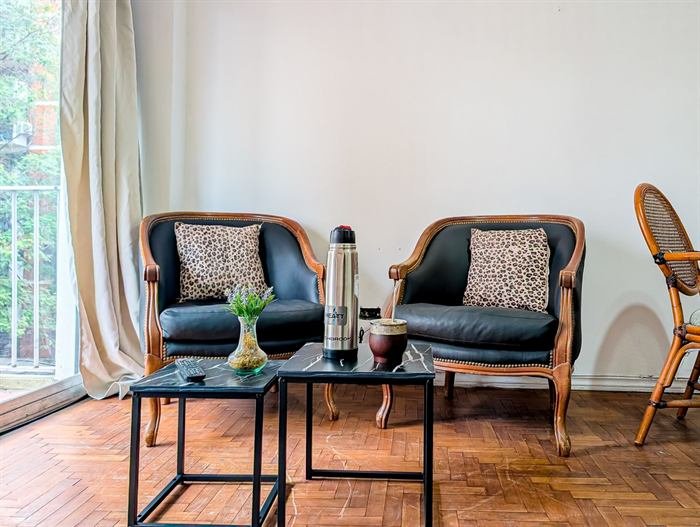 Living con sillones de cuero y piso de parquet en la propiedad de Jaquelina en Rosario